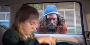 Stuck in traffic just before the crash, Emma prepares to give her sandwich to a homeless man (Josh Quong Tart).