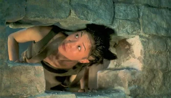 Min Farshaw climbs through the wall into the cell next door.