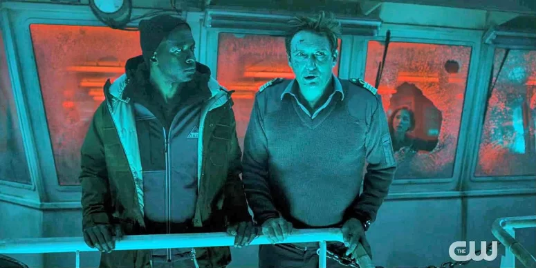 Yonv Joseph and Oliver Masucci - Lit by the glow of the Yrr that surround the ship, Chief Officer Mousa Kofi (Yonv Joseph) and Captain Jasper Alban (Oliver Masucci) discuss the situation. The Communications Officer is visible through the broken window behind them. Kofi's home town of Lekki was in the path of the recent tsunami - Der Schwarm