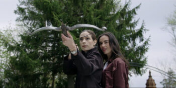 Hazel (Cara Gee) teaches Sheila (Kathleen Munroe) how to shoot a crossbow - Birdland