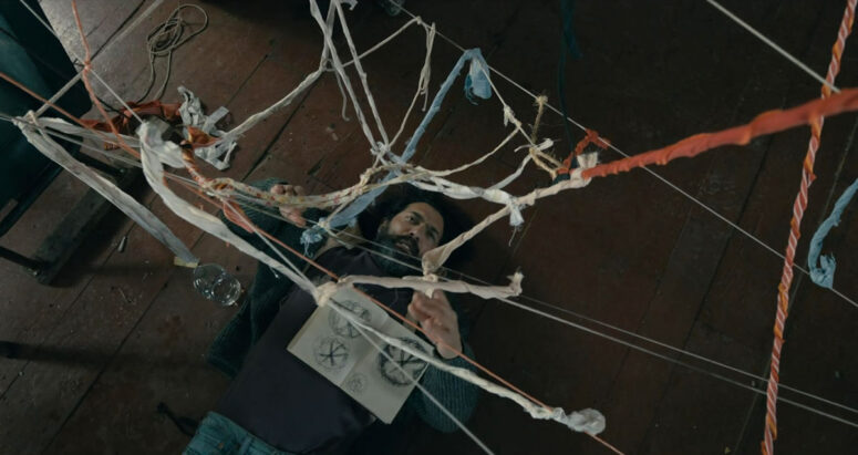 Jade (David Alpay) developing a string-illustrated theory of the drawing he is holding - From