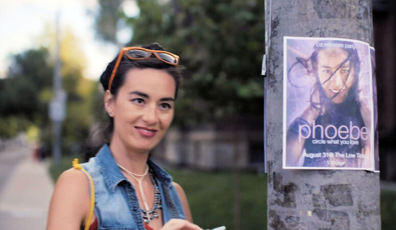 Phoebe (Cara Gee) with poster - Red Rover