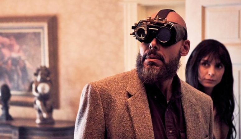 August Ripley (Maurice Dean Wint) and his goggles in the SurrealEstate pilot. Megan Donovan (Tennille Read) is in the background.