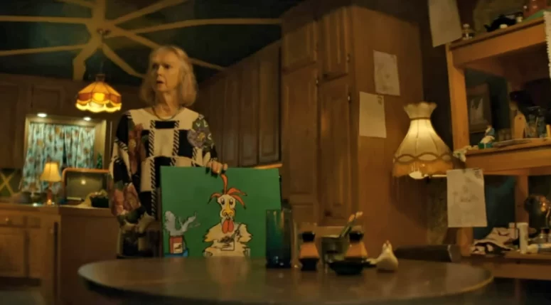 Wendy Lyon as Mrs. Check with one of her paintings.