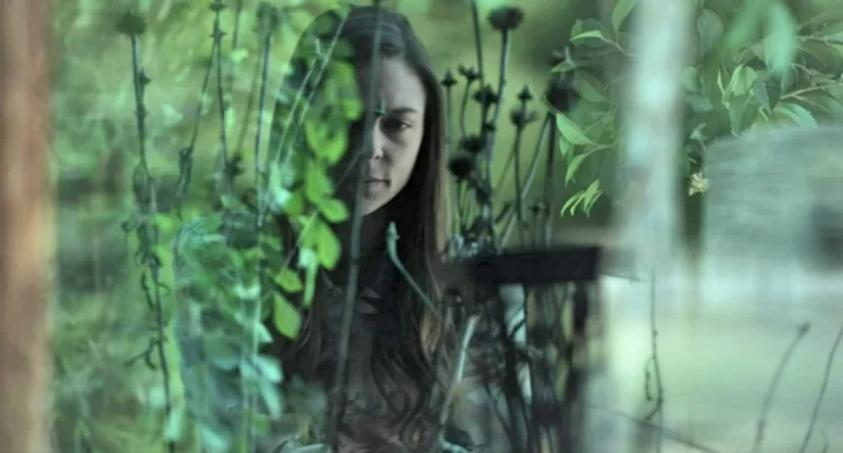 Janis (Sara Mitich) listens from the garden as Clatyon speaks to Kai on the phone - Olivia