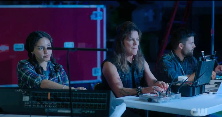 A tech (Cecilly Day) and Pyro Poppy (Jill Teed) monitor a band rehearsal - Wild Cards 302