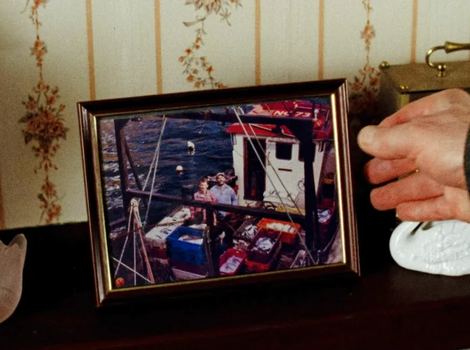 Mr. Richardson picks up an old photo of Luck on the deck of the boat - Rose of Nevada